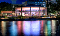 A photo of a brightly lit carouse in Spokane WA with colorful reflections on the water. 